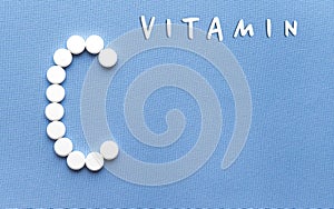 Vitamin C is lined with white pilules on a blue background close-up.