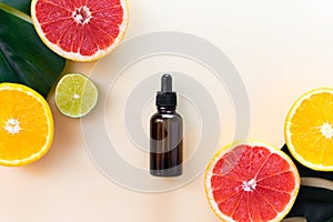 Vitamin C serum in an amber bottle with a pipette on a background of orange citrus fruits with green leaves. Citrus