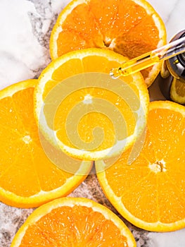 Vitamin C serum bottle with dropper on white marble background