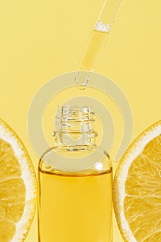 Vitamin c skincare serum. Anti wrinkle fluid serum with antioxidant action. dropper pipette between two orange slices on