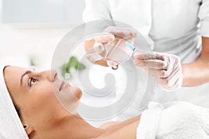 Vitamin cocktail in an ampoule, a woman in the beauty salon