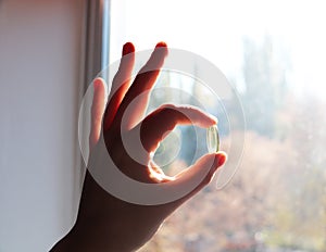 Vitamin D or omega 3 capsules. Vitamin gel in hand against the window. The concept of a lack of vitamin D in the body