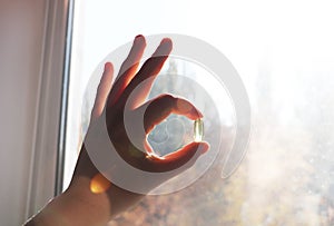 Vitamin D or omega 3 capsules. Vitamin gel in hand against the window. The concept of a lack of vitamin D in the body