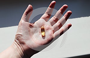 Vitamin D or omega 3 capsules. Vitamin gel in hand against the window. The concept of a lack of vitamin D in the body