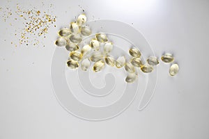 Vitamin D3 gelatin capsules on white background. The fat-soluble solar vitamin cholecalciferol glows yellow and glistens.