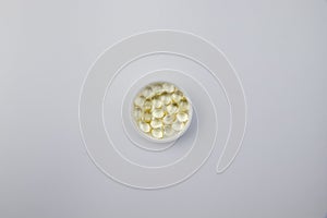Vitamin D3 gelatin capsules on white background. The fat-soluble solar vitamin cholecalciferol glows yellow and glistens.