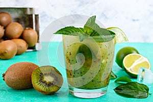 Vitamin drink with kiwi, mint, lime, soda in a glass on a bright background.
