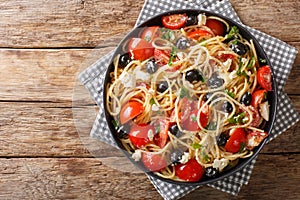 Vitamin fresh greek pasta spaghetti salad with cheese and vegetables close-up on a plate. Horizontal top view