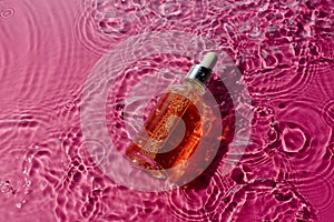 Vitamin narutal serum in a glass bottle in water surrounded on pink
