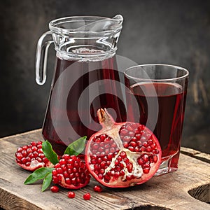Vitamin pomegranate juice in a glass and a jug, near an open juicy pomegranate on a cutting board