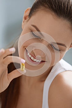 Vitamin. Smiling woman with omega 3 pill, fish oil capsule