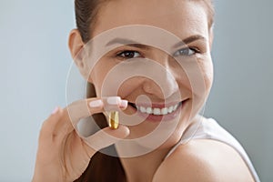 Vitamin. Smiling woman with omega 3 pill, fish oil capsule