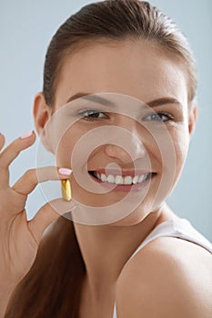 Vitamin. Smiling woman with omega 3 pill, fish oil capsule