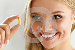 Vitamin And Supplement. Beautiful Woman Holding Fish Oil Capsule