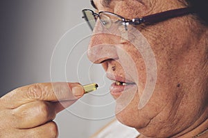 Vitamin And Supplement. Closeup Of Beautiful Old Woman Taking Yellow Fish Oil Pill