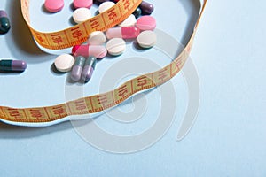 Vitamin tablets and capsules and bright yellow measuring tape on a blue background