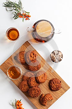 Vitamin tea with herbs and sea buckthorn, cereal gluten-free cookies with dried fruits on a wooden board. Healthy food, tea drink