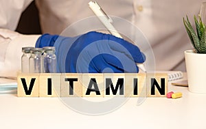 Vitamin word from white cubes on blue background. Vitamins A B C D E, healthy and medical concept