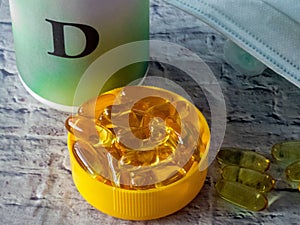 Vitamine D capsules near plastic conainer and medical face masks on the table