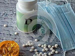 Vitamine D tablets near plastic conainer and medical face masks on the table