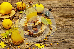 Vitaminic healthy sea buckthorn tea in small glass jars with fresh berries and autumn decor