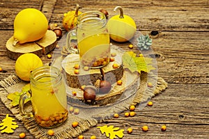 Vitaminic healthy sea buckthorn tea in small glass jars with fresh berries and autumn decor