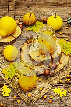 Vitaminic healthy sea buckthorn tea in small glass jars with fresh berries and autumn decor