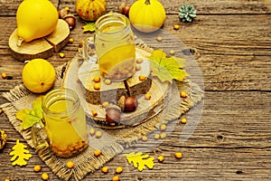 Vitaminic healthy sea buckthorn tea in small glass jars with fresh berries and autumn decor