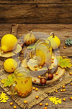 Vitaminic healthy sea buckthorn tea in small glass jars with fresh berries and autumn decor