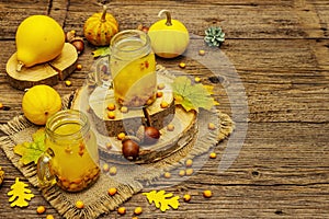 Vitaminic healthy sea buckthorn tea in small glass jars with fresh berries and autumn decor