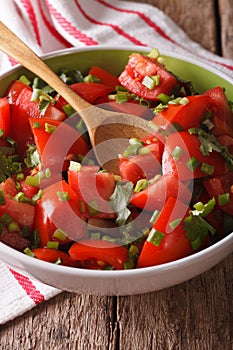 Vitaminic tomato salad with herbs close up in a bowl. vertical