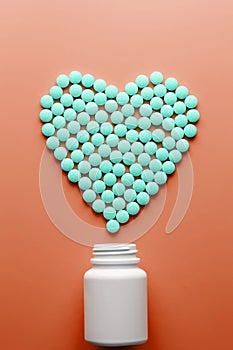 Vitamins B 12 on a red heart-shaped substrate, poured out of a white jar