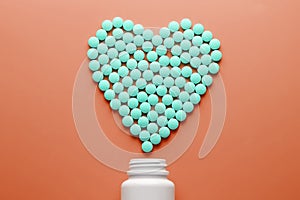 Vitamins B 12 on a red heart-shaped substrate, poured out of a white jar.