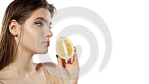 Vitamins. Beautiful young woman with lemon slice over white background. Cosmetics and makeup, natural and eco treatment