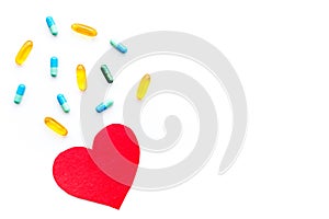 Vitamins of drugs for heart. Color pills near heart sign on white background top view copy space