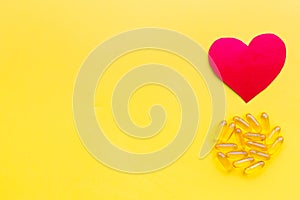 Vitamins of drugs for heart. Color pills near heart sign on yellow background top view space for text