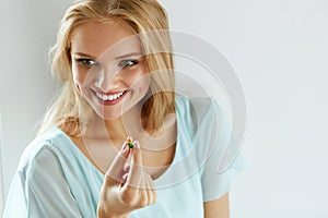 Vitamins And Food Supplements. Beautiful Woman With Pill In Hand