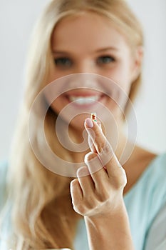 Vitamins And Food Supplements. Beautiful Woman With Pill In Hand