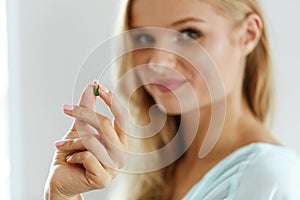 Vitamins And Food Supplements. Beautiful Woman With Pill In Hand