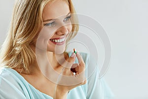 Vitamins And Food Supplements. Beautiful Woman With Pill In Hand