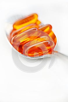 Vitamins, gel caps on a spoon