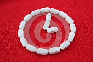 Vitamins and generics, pharmacy and medicine concept. Watch from white pills on a red background. Top view, place for text. Medici