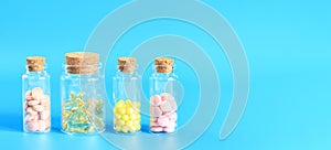 Vitamins in glass bottles on a blue background, side view, copy space