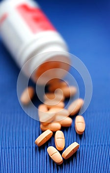 Vitamins are poured out on a dark blue table. A sm