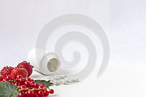 Vitamins supplements as a capsule with fresh berries from medicine white pill bottle on white background