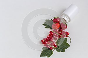 Vitamins supplements as a capsule with fresh berries from medicine white pill bottle on white background