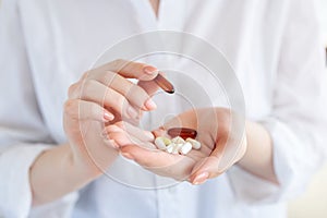 Vitamins And Supplements. Closeup of hand holding variety of white pills on palm. Close-up Of Medication Tablets, Capsules From