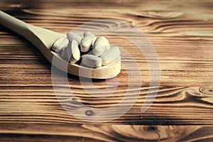 Vitamins or supplements in wooden spoon on vintage wooden board