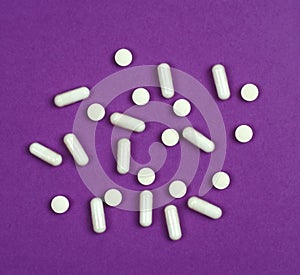 Vitamins in white tablets on a purple background