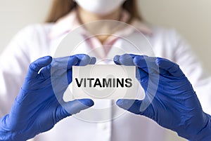 Vitamins word on white paper board in doctor hands. health concept